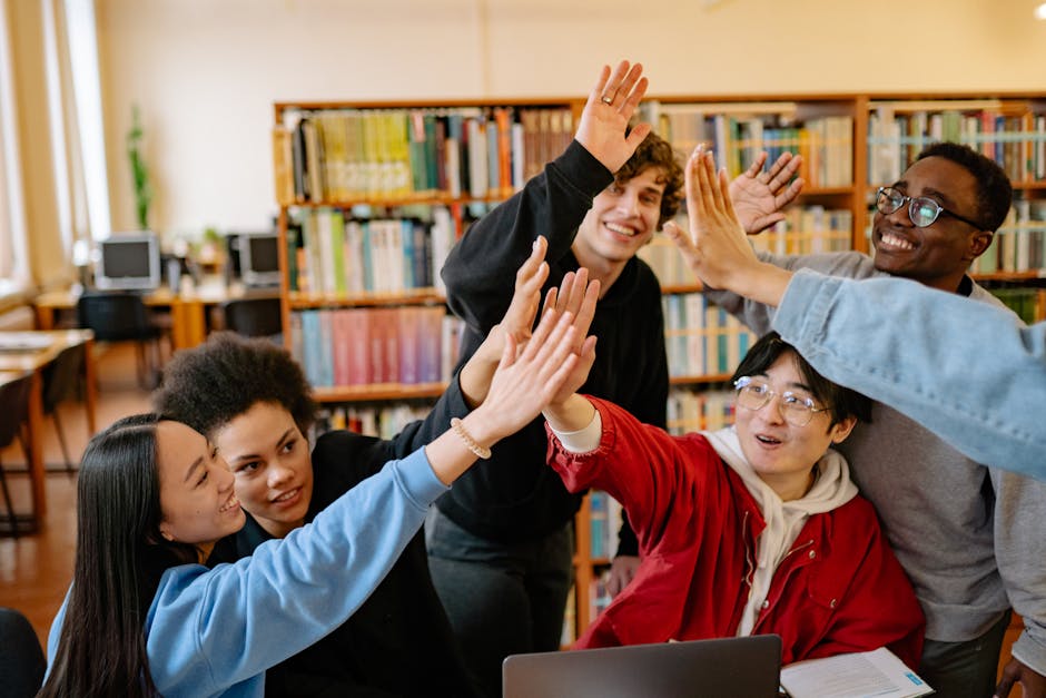 Group of happy students high-fiving in a library setting, celebrating success